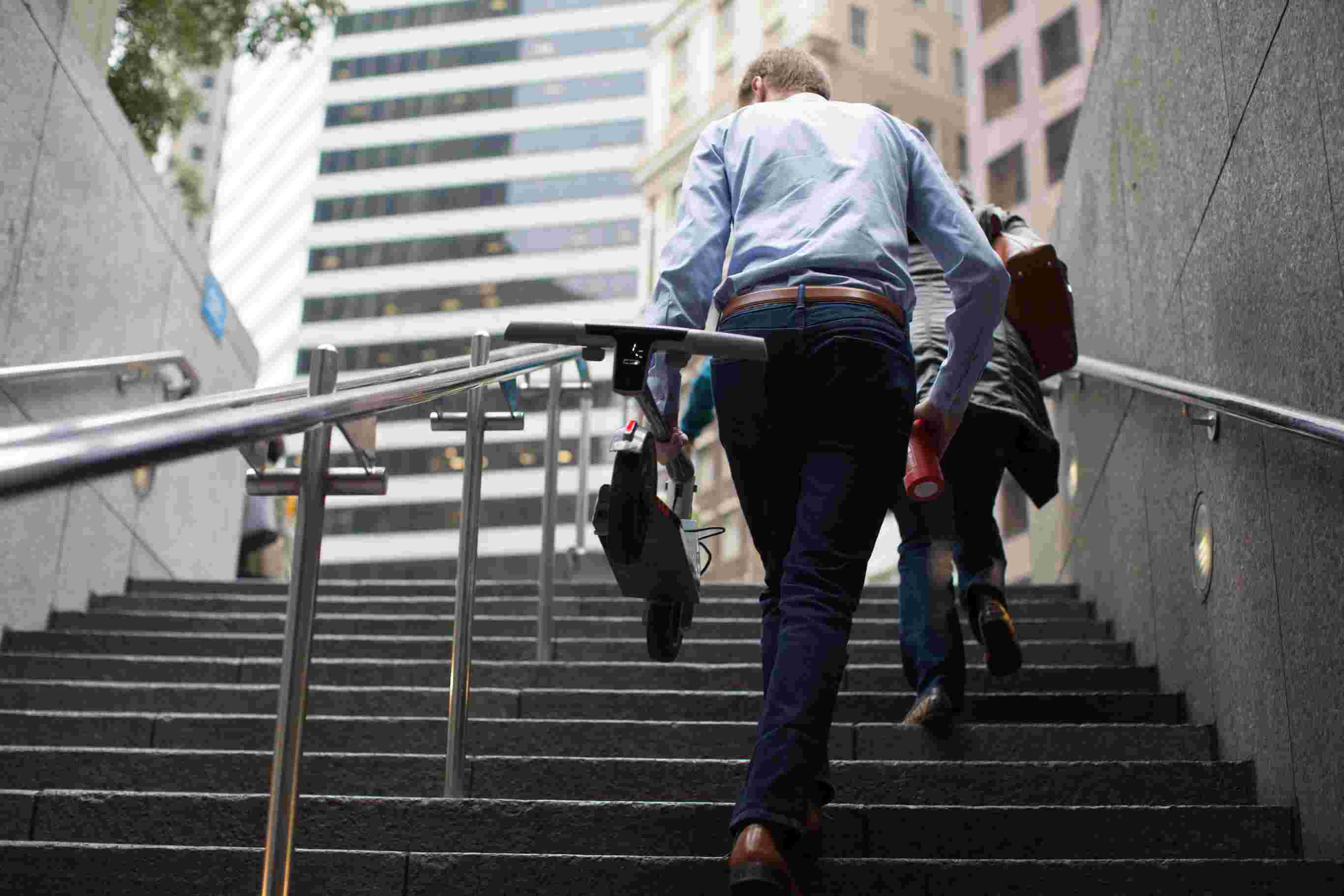 Man Walking Up Stairs Portable Electric Scooter Commute