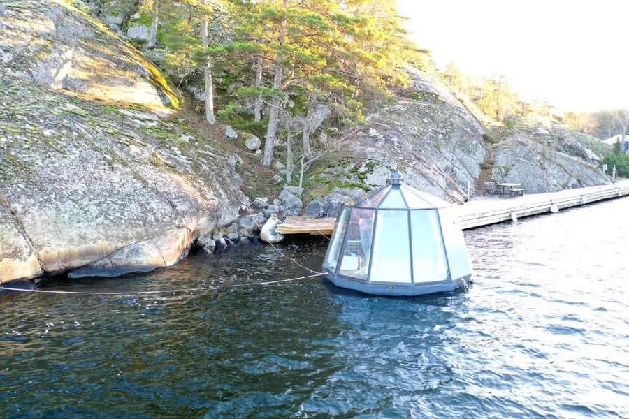 Igloohytten flyter på vattnet intill klipporna