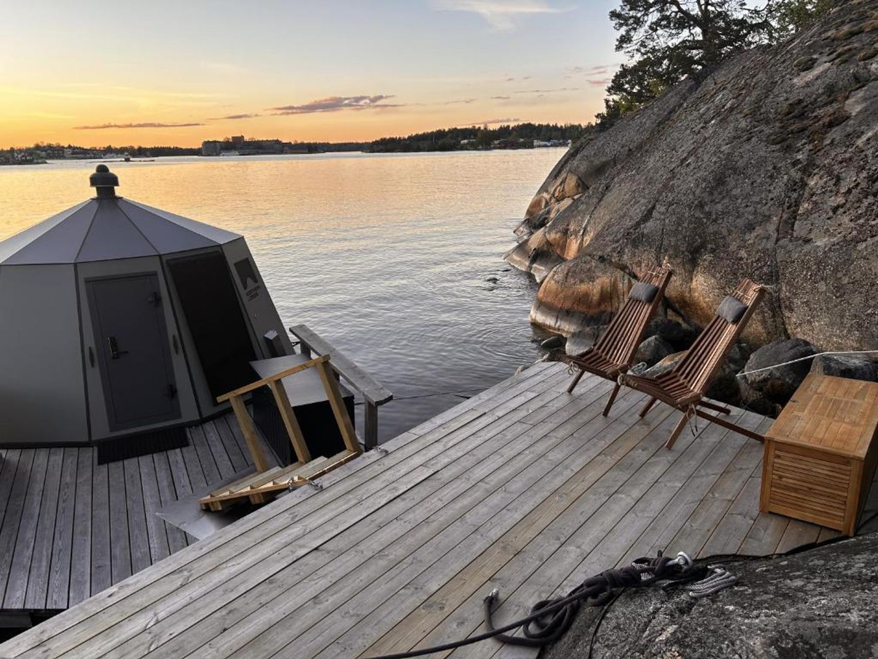 Trädäcket med solstolar framför hytten i solnedgång