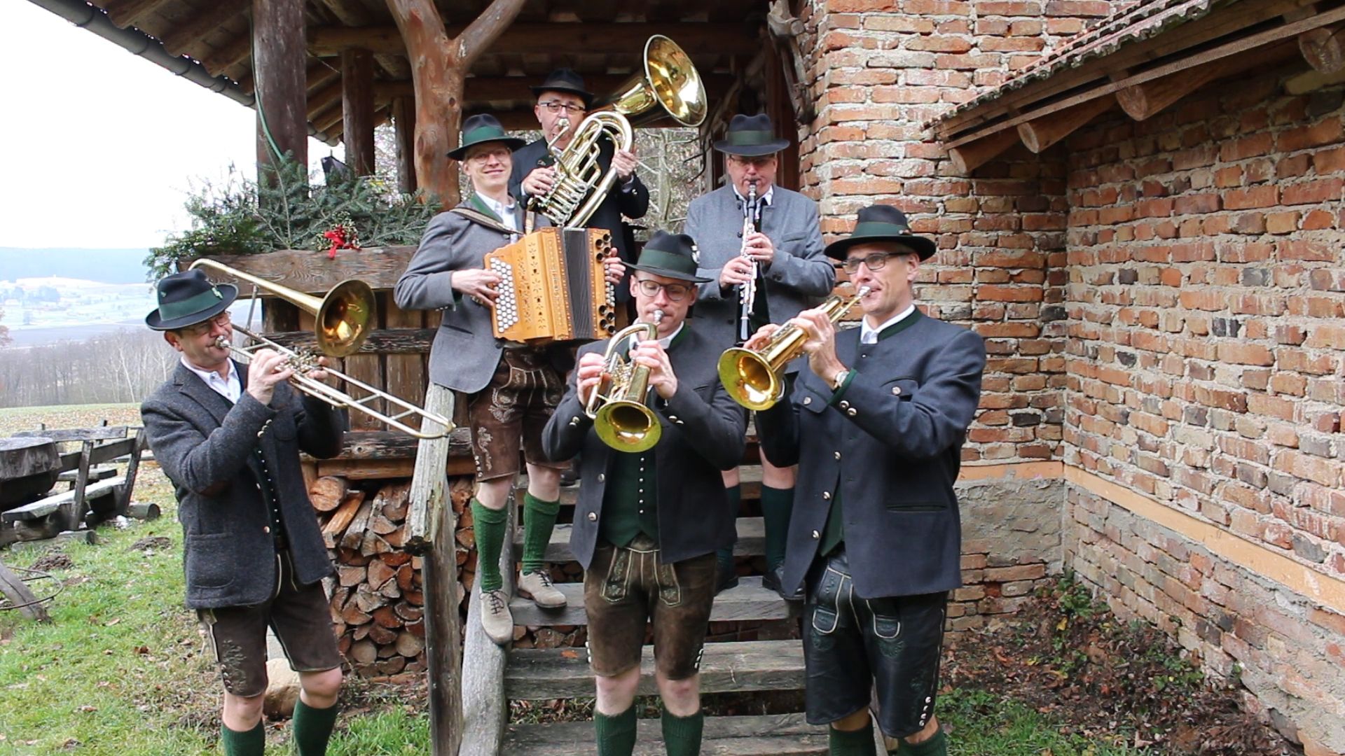 Die Musker mit ihren Instrumenten auf einer Holzstiege vor einem Backsteinhaus
