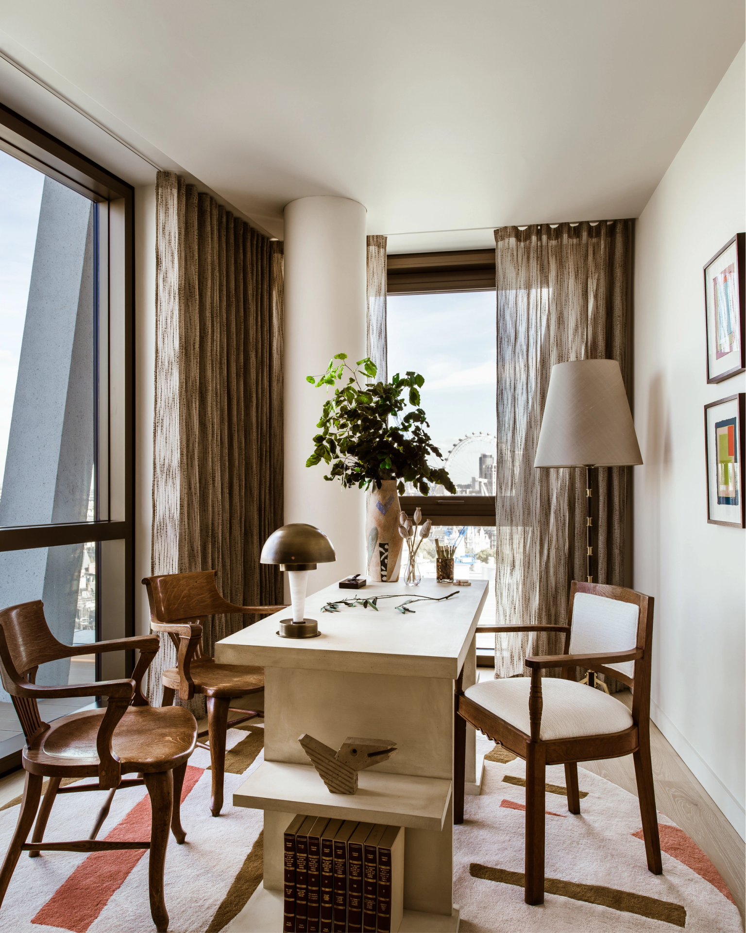 Light-filled study with mid-century chairs and sculptural desk, where floor-to-ceiling windows frame a striking view of the London Eye.