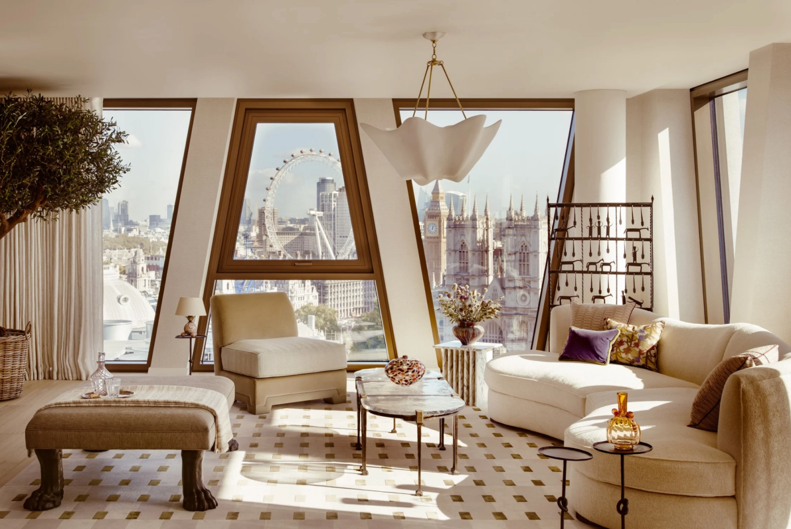 Westminster penthouse living room with custom furnishings, sculptural lighting and panoramic views of the London Eye and Westminster Abbey through angled floor-to-ceiling windows.