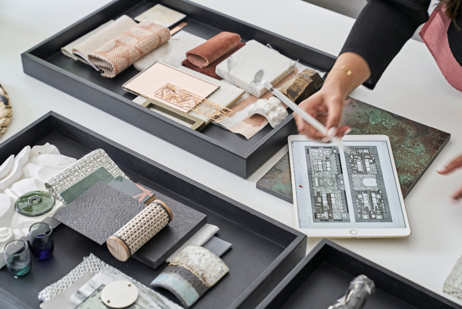 Designers assessing material trays and architectural layouts during a concept development session.