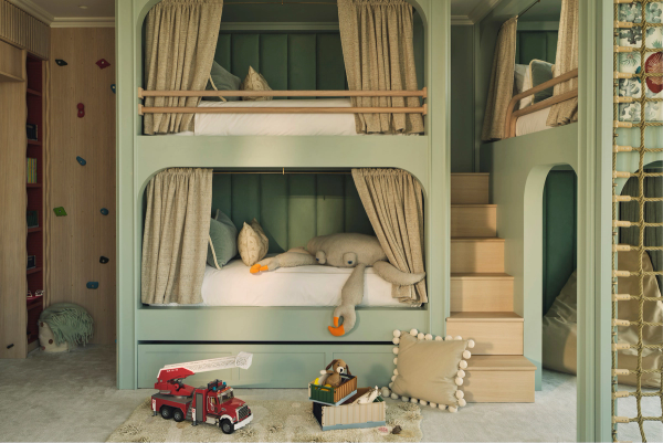 Playful children’s bedroom with built-in mint green bunk beds, climbing wall, rope ladder and soft furnishings, designed for imaginative play and cosy sleepovers.