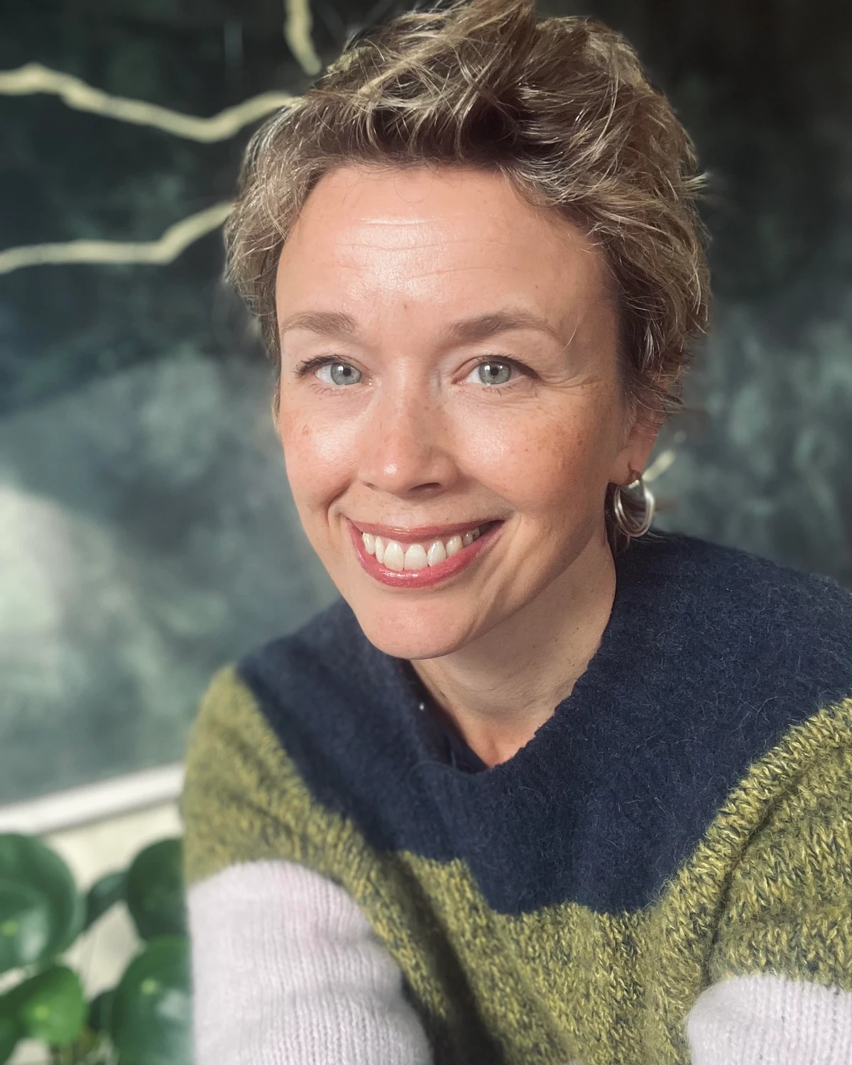 Leende Lisa Tallroth, Moderator och Programledare i flerfärgad stickad tröja mot naturbakgrund