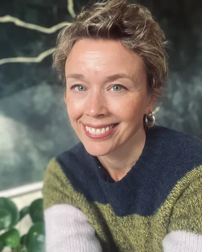 Leende Lisa Tallroth, Moderator och Programledare i flerfärgad stickad tröja mot naturbakgrund