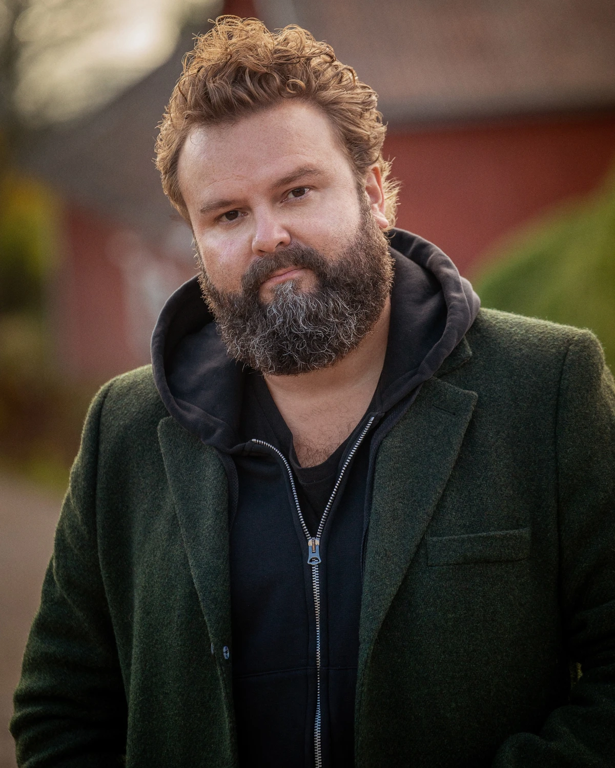 Niklas Turner Olovzon kollar in i kameran, han är en författare & Entréprenör i hoodie och mörkgrön kavaj