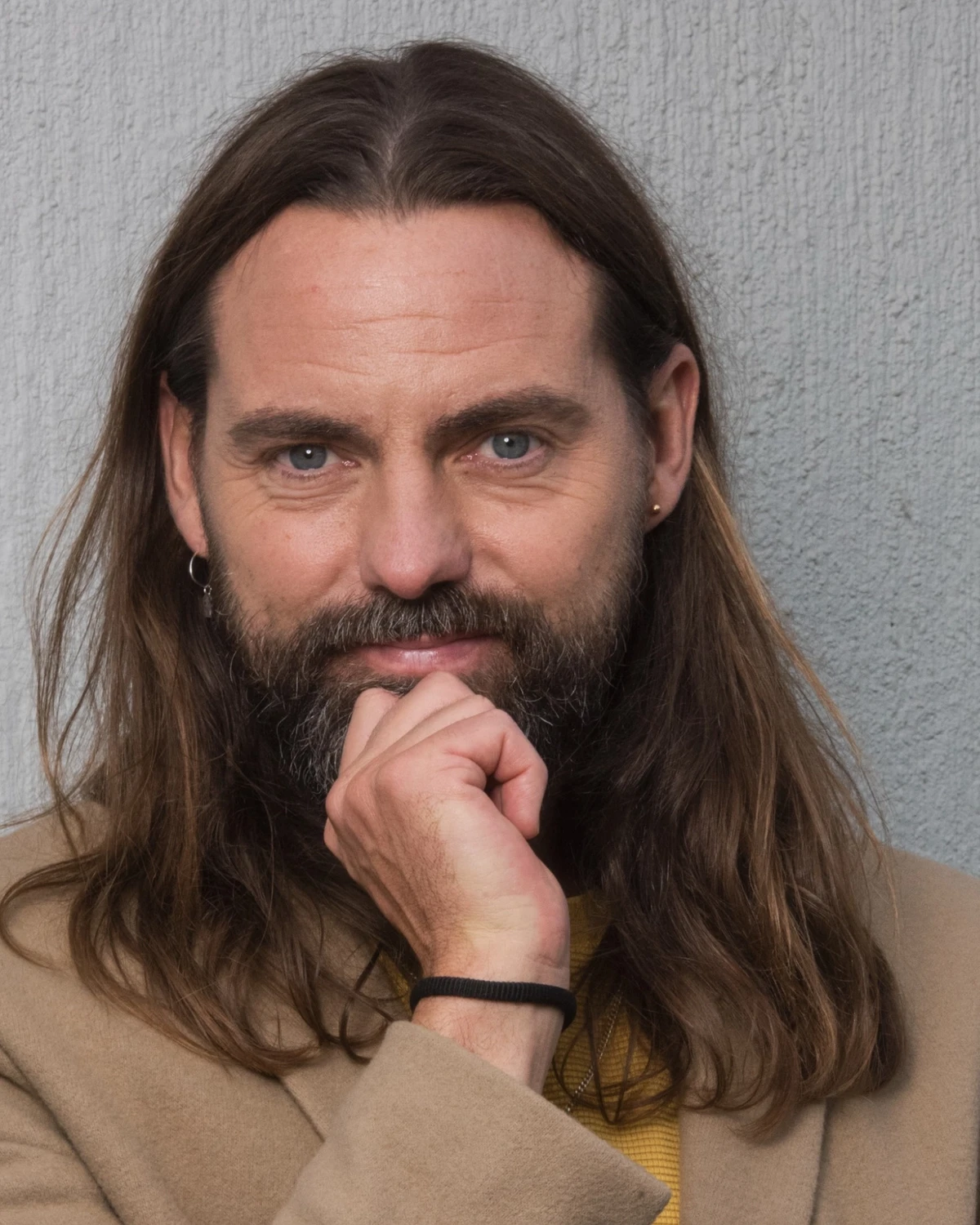 Skribent och Programledare Nisse Edwall med handen mot hakan i beige kavaj