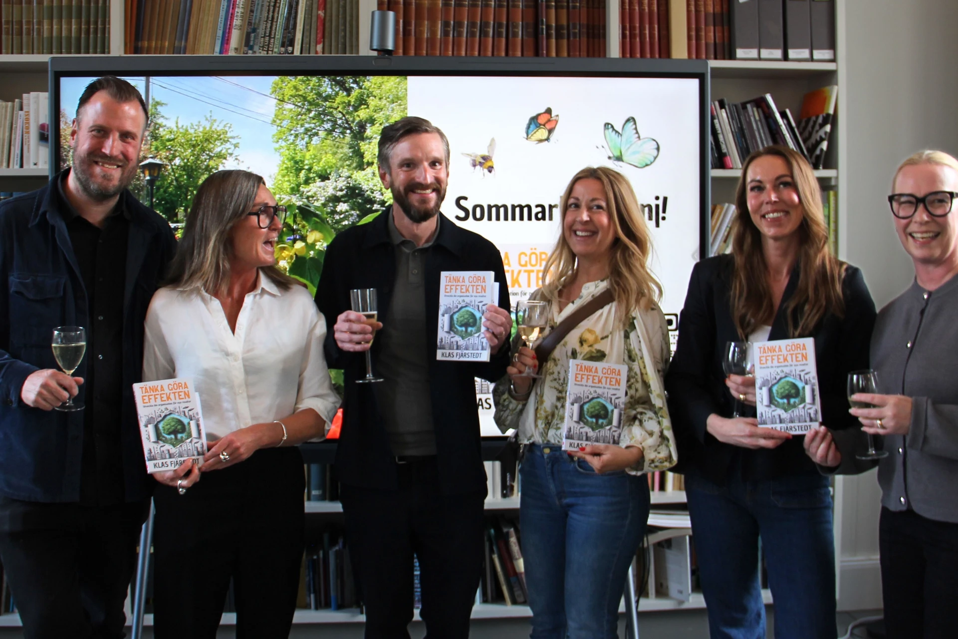 Christian von Essen, Anna-Lena Hernvall, Klas Fjärstedt, Alexandra Appelqvist, Sara Sandberg Frantzén och Charlotte Sirc till står skrattande tillsammans, några med bok och glas i handen, framför bokhyllor i en salong..