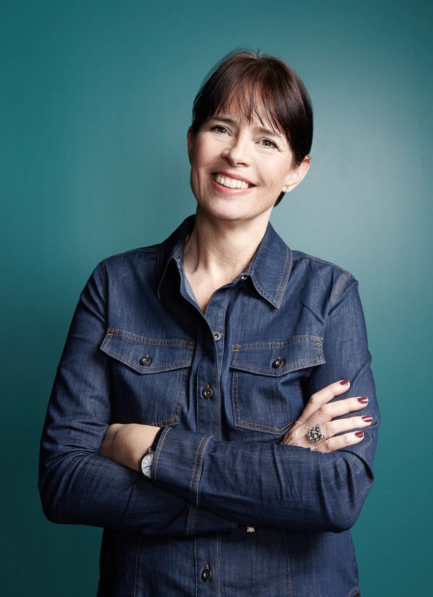Den hyllade författaren och kommunikatören Christina Knight i mörk jeansskjorta mot blå bakgrund