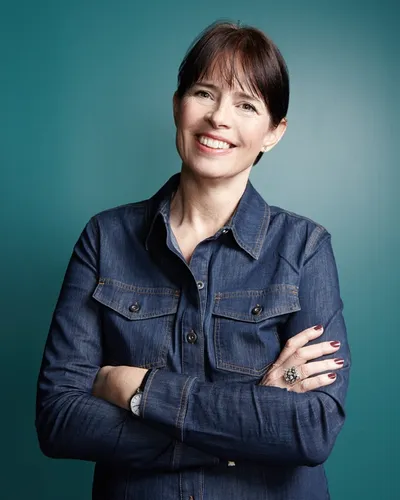 Den hyllade författaren och kommunikatören Christina Knight i mörk jeansskjorta mot blå bakgrund