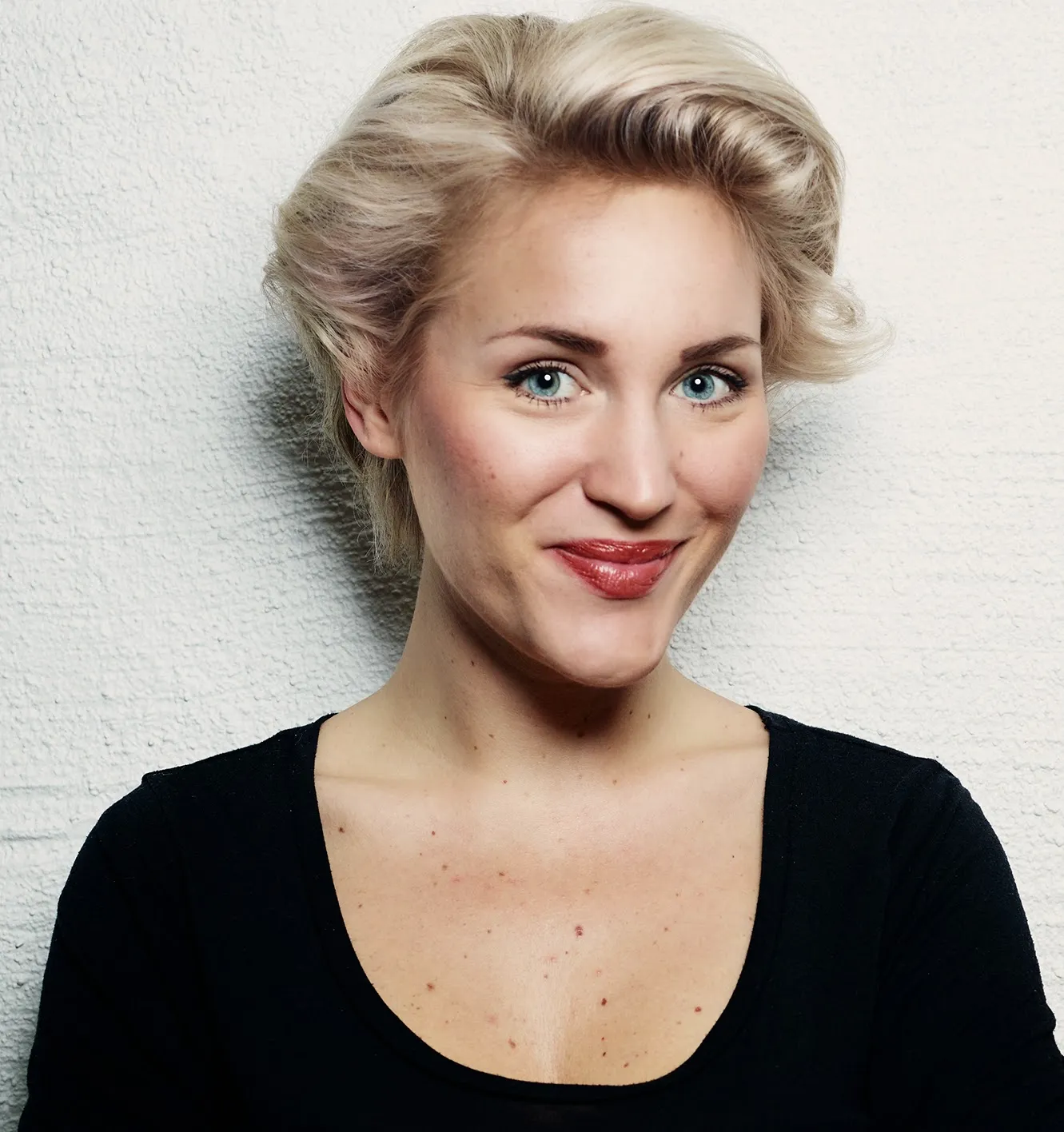Anja Melander i kort, blont hår och en svart topp ler mot kameran. 