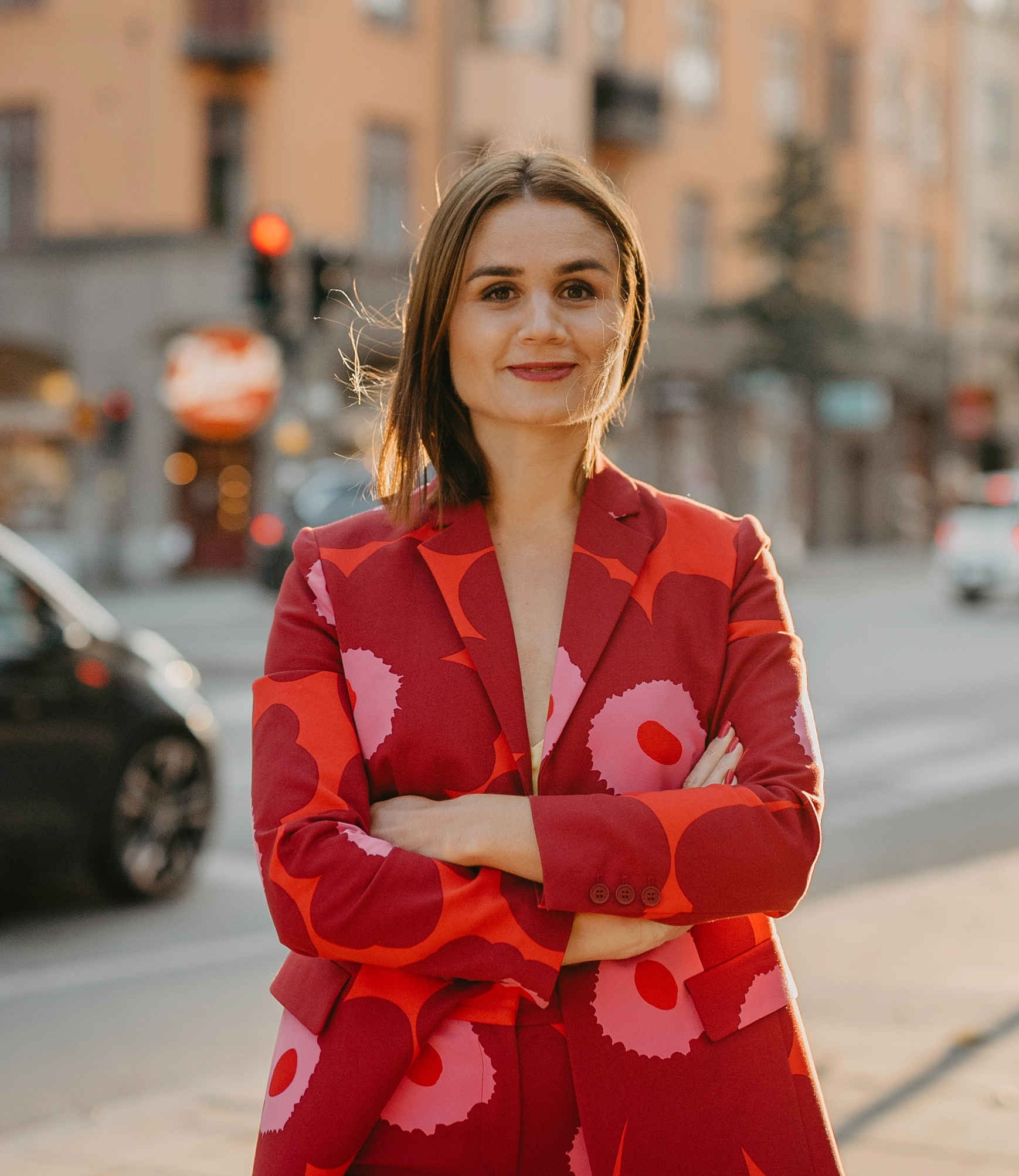 Bilden visar AI-experten och techprofilen Paulina Modlitba som står leende i röd kavaj med trafik i bakgrunden.