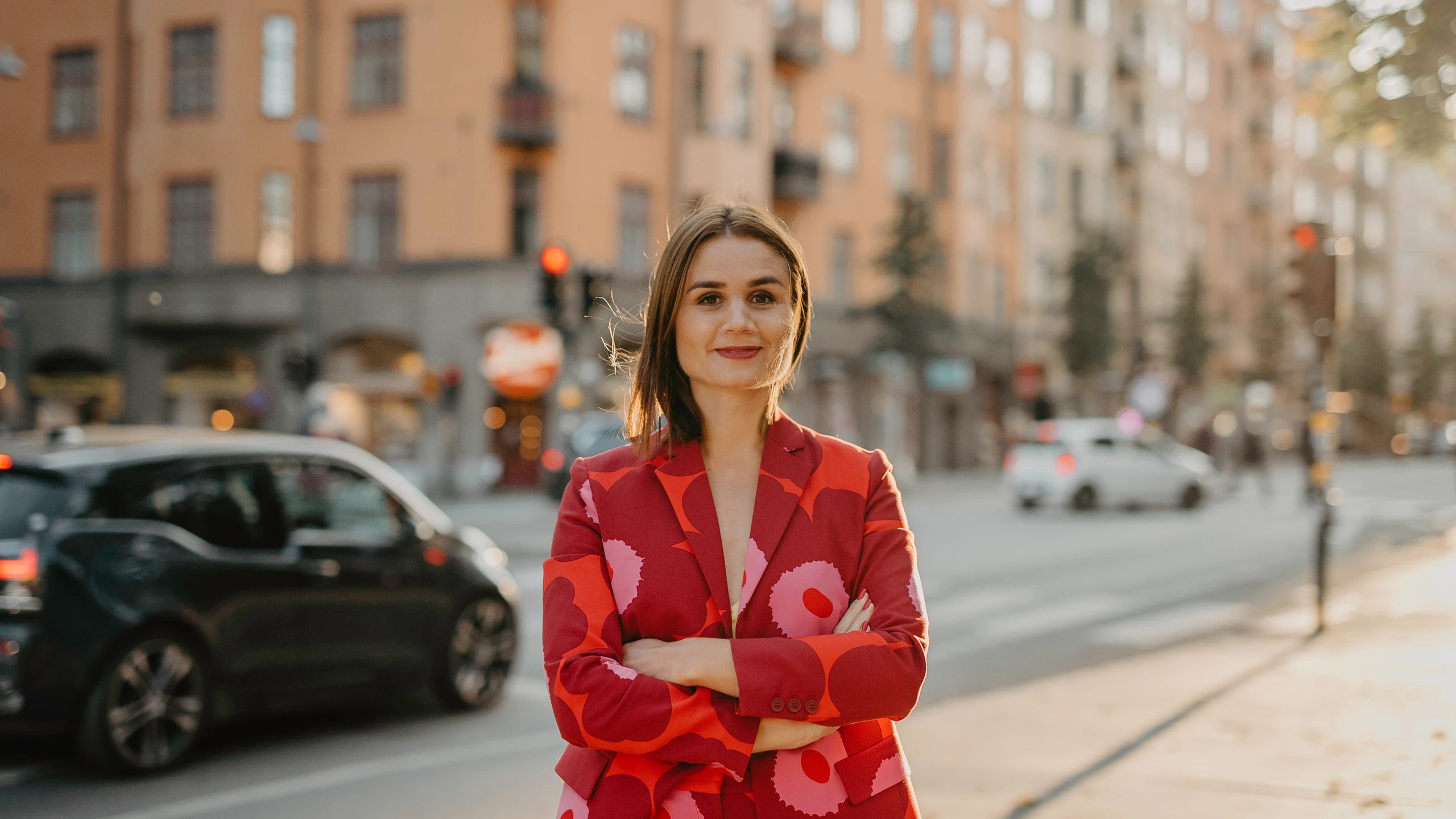 BYWRTRS AI-expert och techprofil Paulina Modlitba i blommig röd kavaj med lugn biltrafik bakom sig