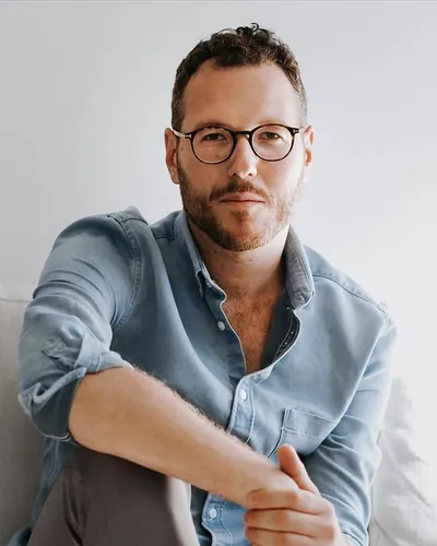 Författare & Sjuksköterska Marcus Jarl sittandes i jeansskjorta med ena knät uppdraget mot bröstkorgen