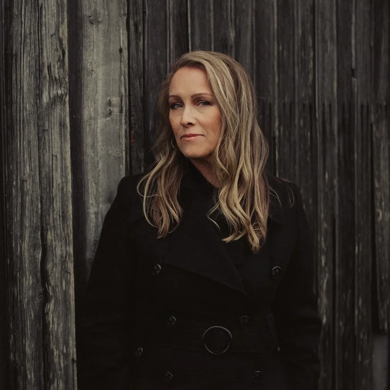 Foto av Kristina Emanuelsson mot en trävägg
