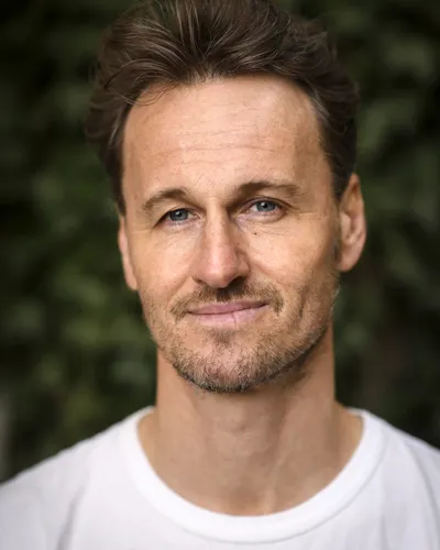 Föreläsaren och Yogaläraren Magnus Fridh i vit t-short med naturen som bakgrund