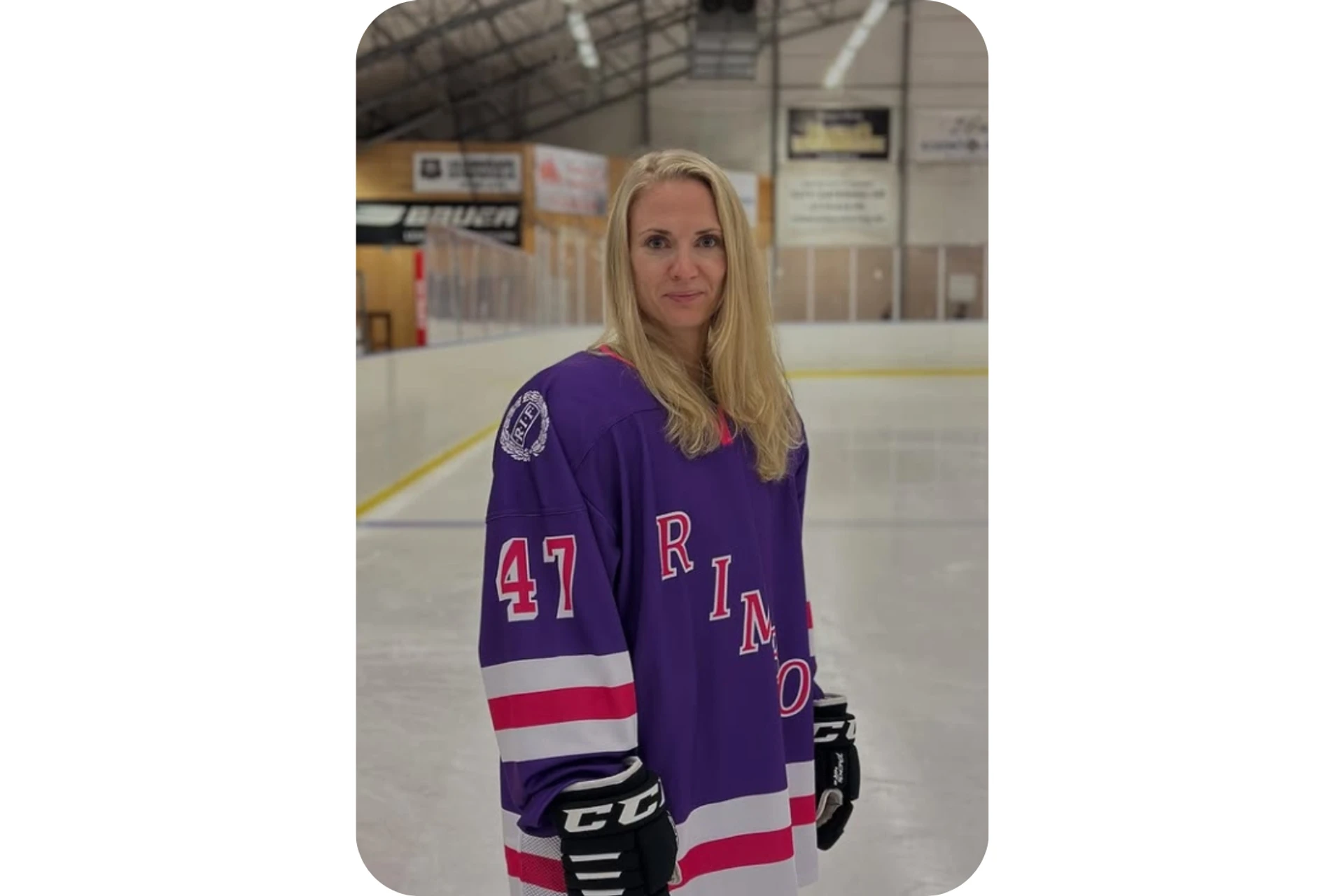 Elisabeth Wadin står på isen i en ishockeyrink iklädd blå hockeytröja och hockeyhandskar.