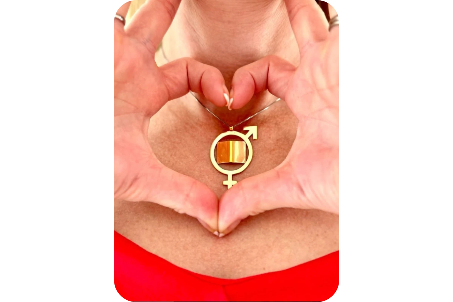 Guldhalsband med bok och manligt och kvinnligt tecken, omgärdat av fingrar som formar ett hjärta. Personen har röd topp.
