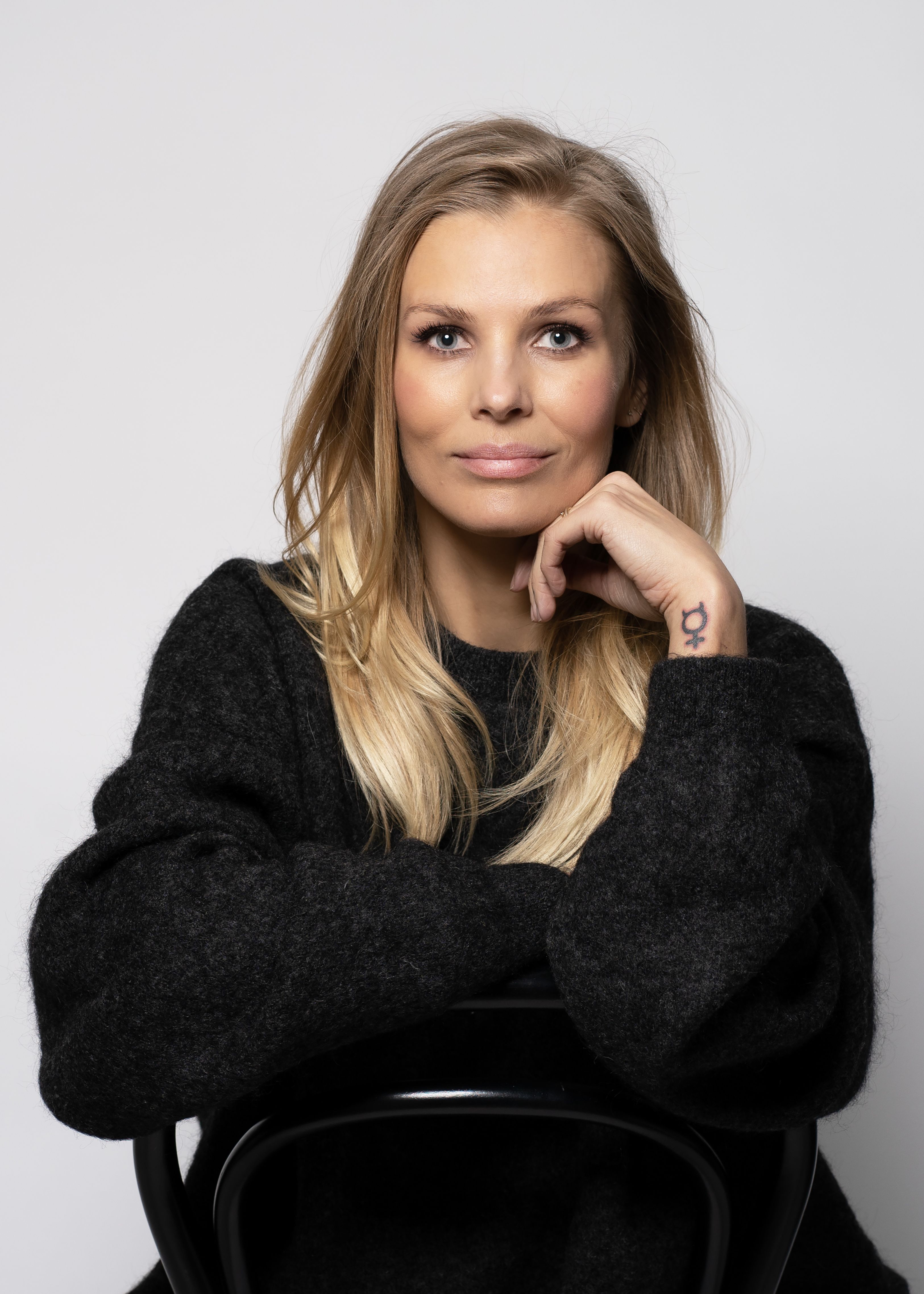 Författaren och debattören Fi Lindfors visar sin tatuering av ett feministiskt kvinnotecken.