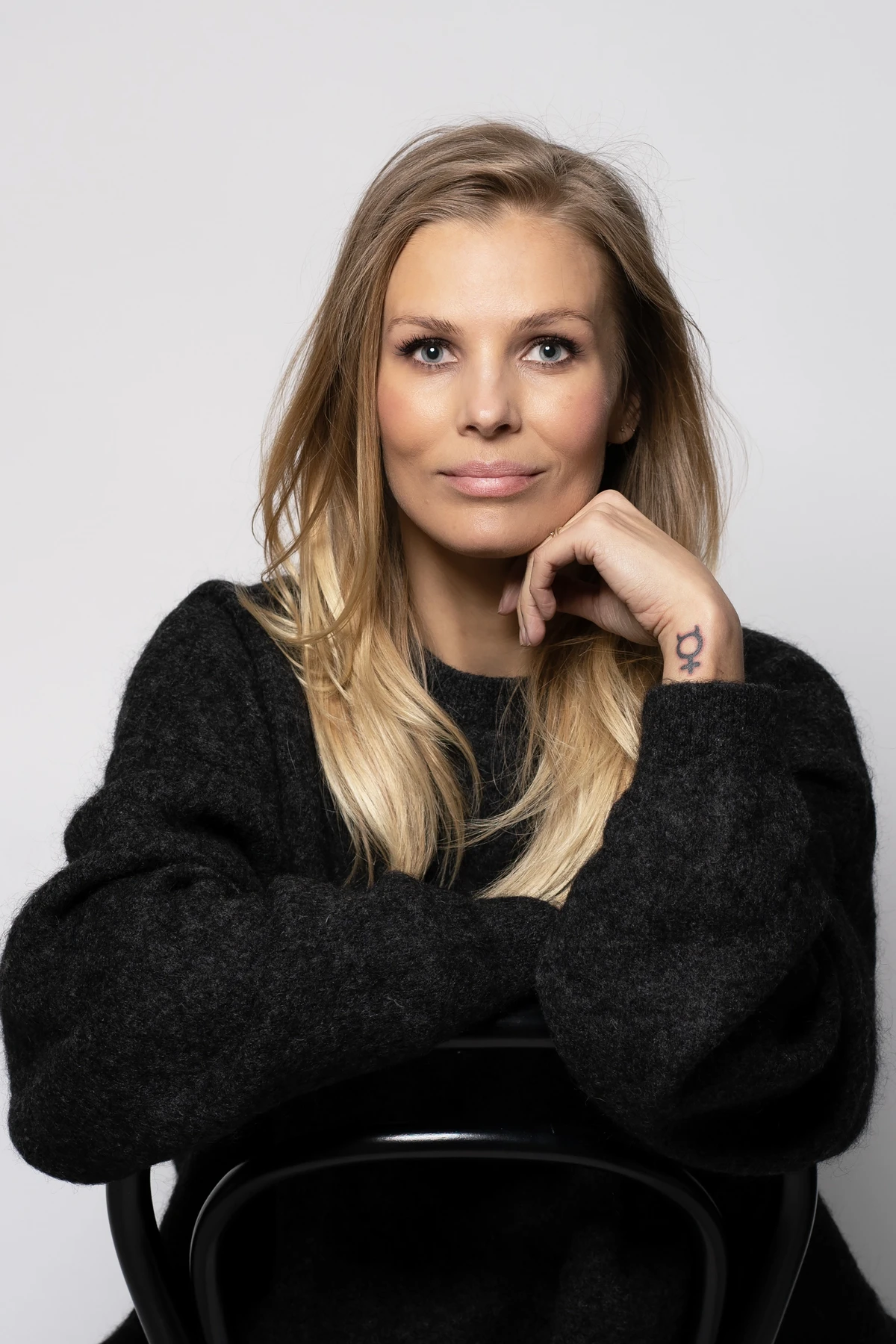 Författaren och debattören Fi Lindfors visar sin tatuering av ett feministiskt kvinnotecken.