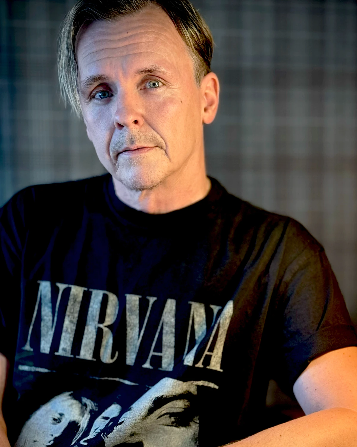 Porträttfoto av Mikael Newihl i svart Nirvana t-shirt mot grårutig bakgrund