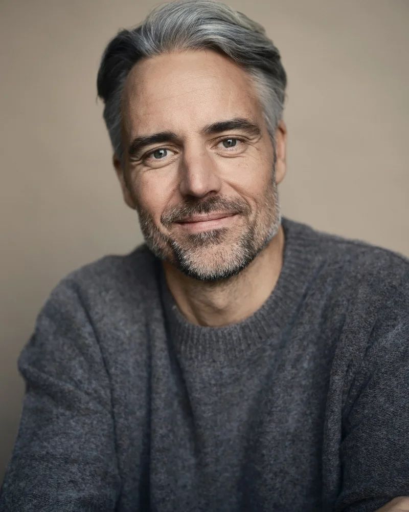 Bilden visar epidemiologen och läkaren Anders Wallensten i en grå stickad tröja och med ett leende på läpparna.