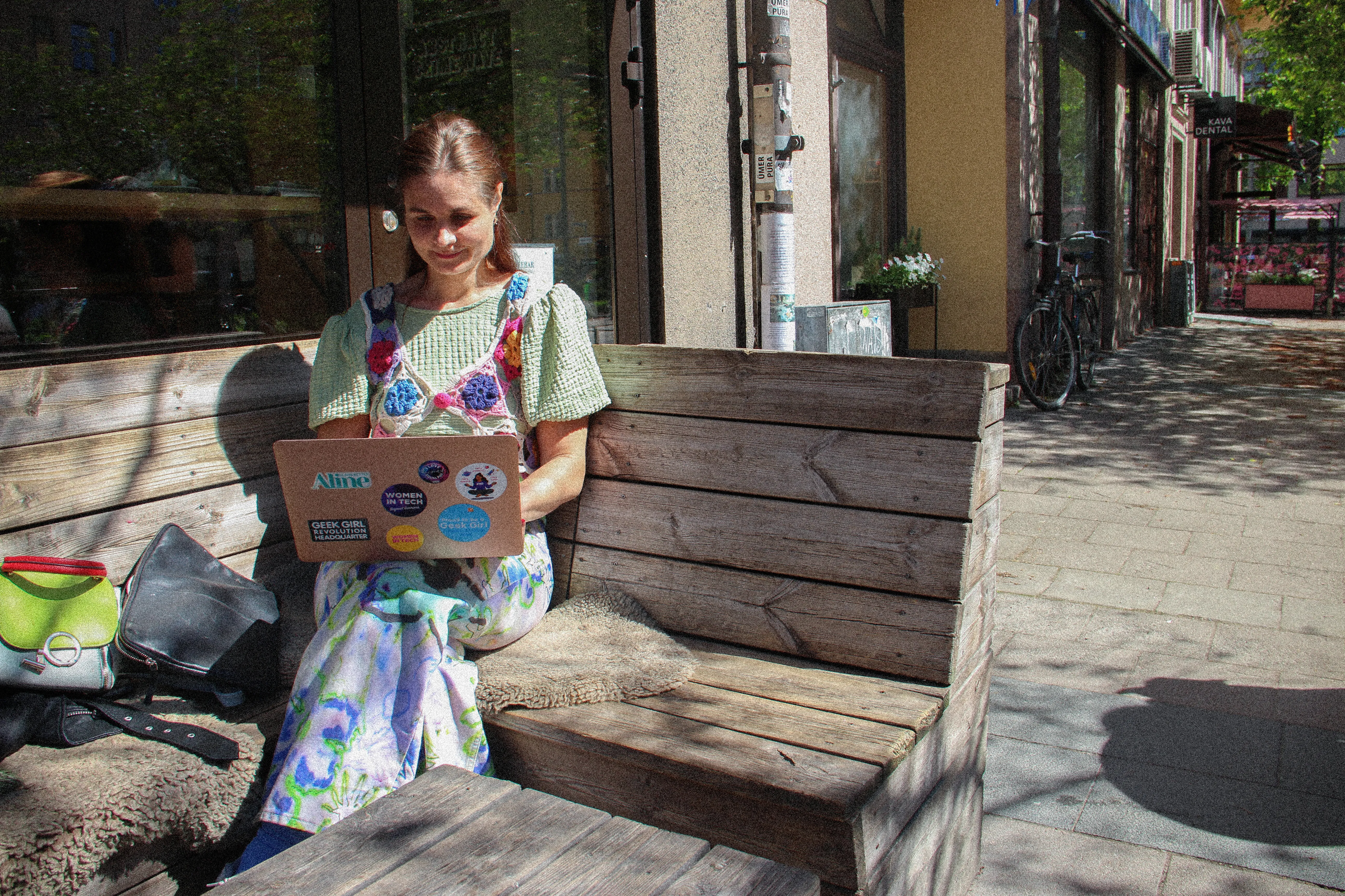 Författaren och techprofilen Paulina Modlitba sitter på en bänk utomhus och jobbar.  