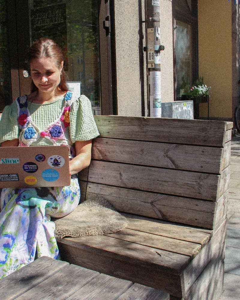 Författaren och techprofilen Paulina Modlitba sitter på en bänk utomhus och jobbar.