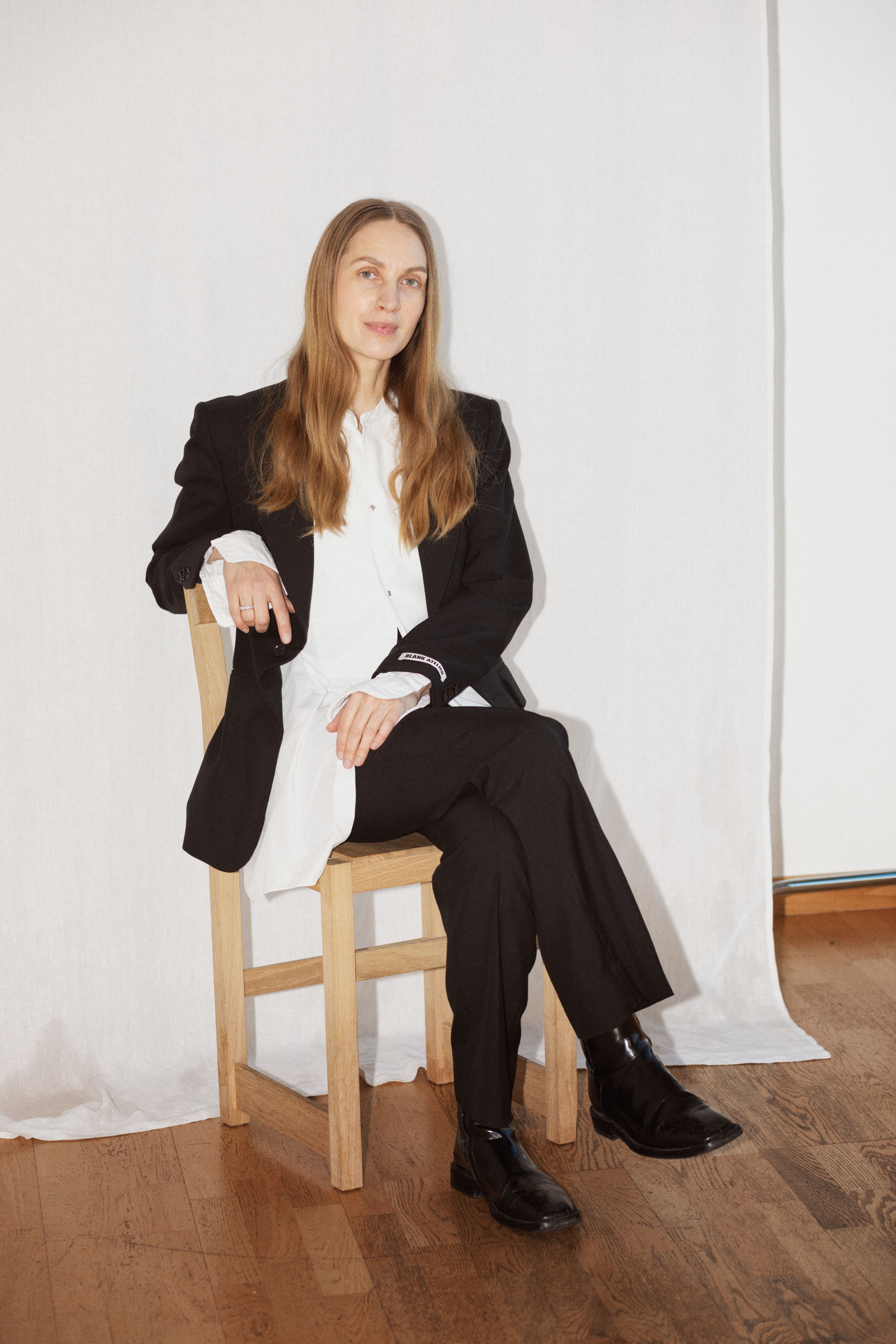 Hållbarhetsspecialisten och författaren Lisa Bergstrand sitter avslappnat på en stol, hon är klädd i svart och vitt.