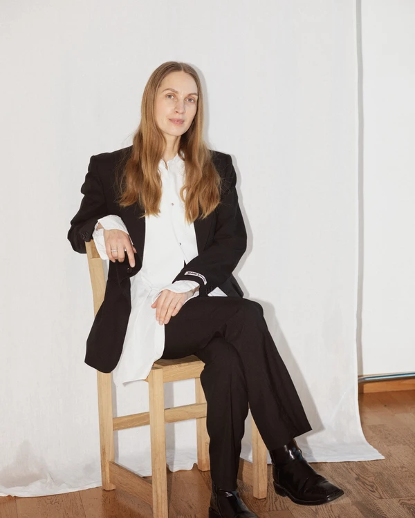Hållbarhetsspecialisten och författaren Lisa Bergstrand sitter avslappnat på en stol, hon är klädd i svart och vitt.