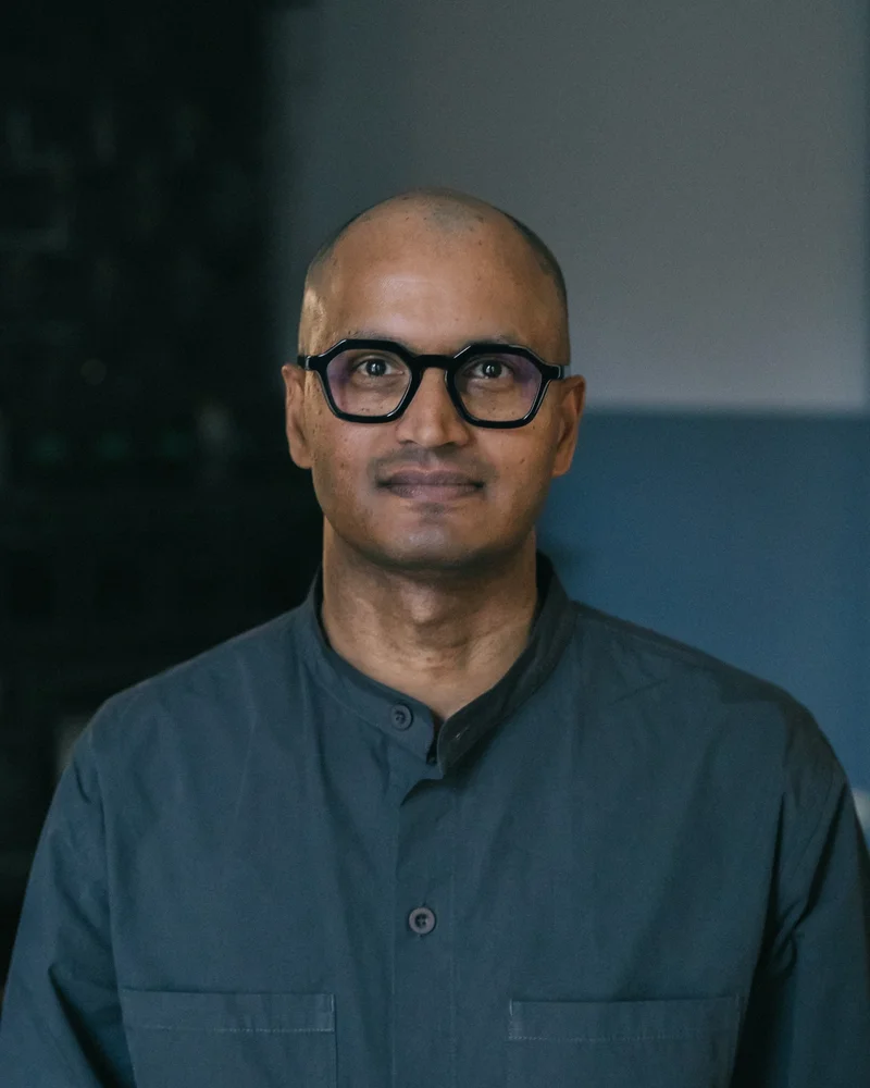 Porträttfoto på Josef Conning klädd i grå skjorta och svarta glasögon