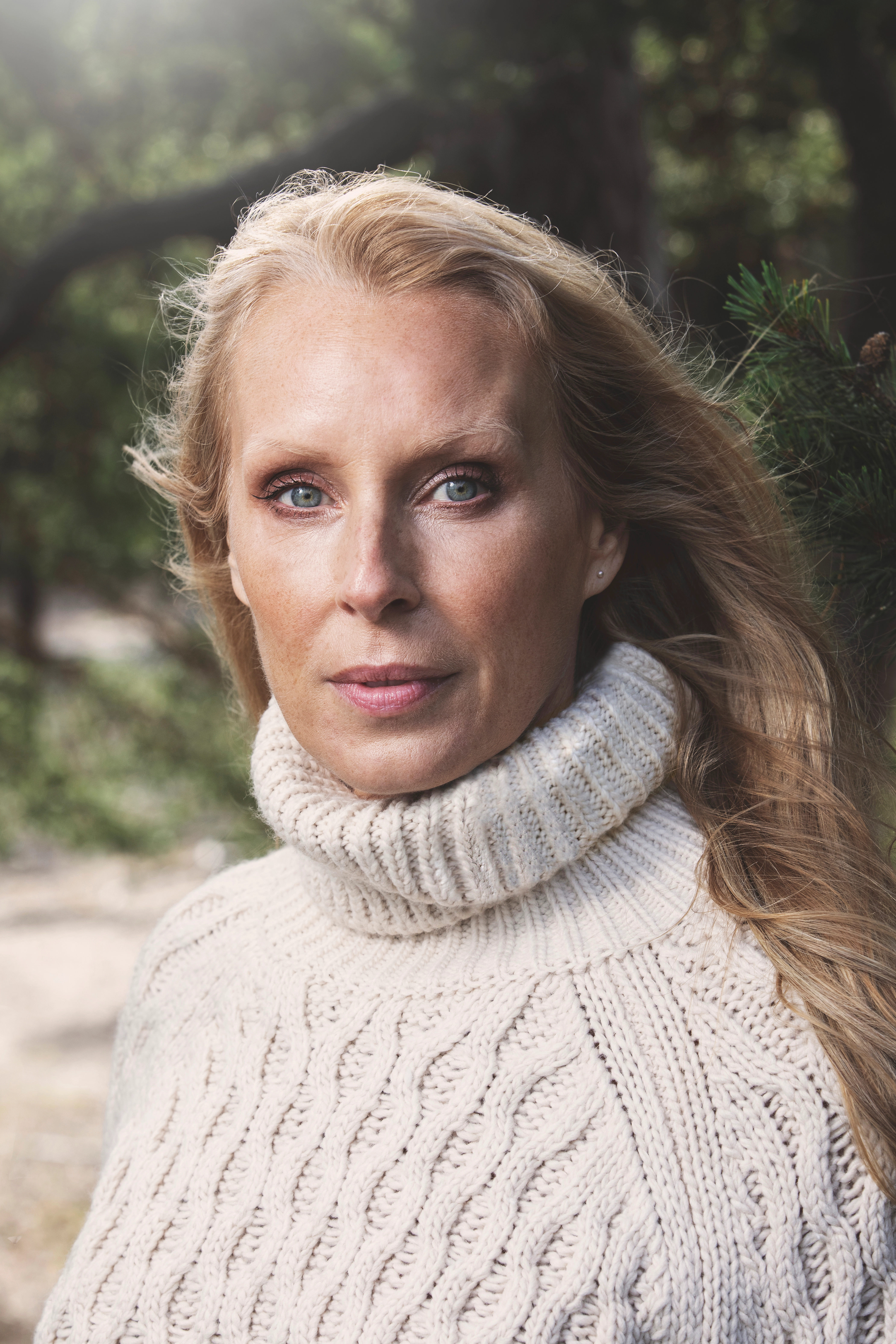 Författareen och Livsinspiratören Tove Oddsdotter i vit stickad tröja med natur som bakgrund
