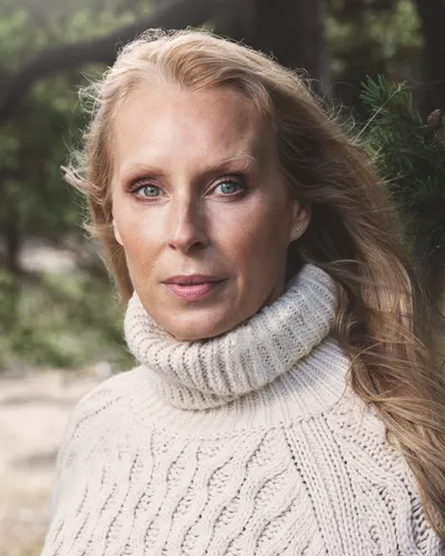 Författareen och Livsinspiratören Tove Oddsdotter i vit stickad tröja med natur som bakgrund