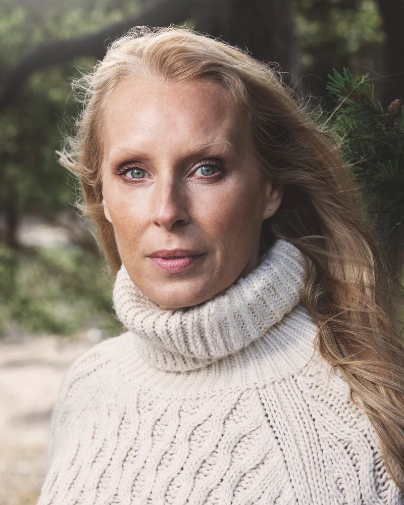 Författareen och Livsinspiratören Tove Oddsdotter i vit stickad tröja med natur som bakgrund