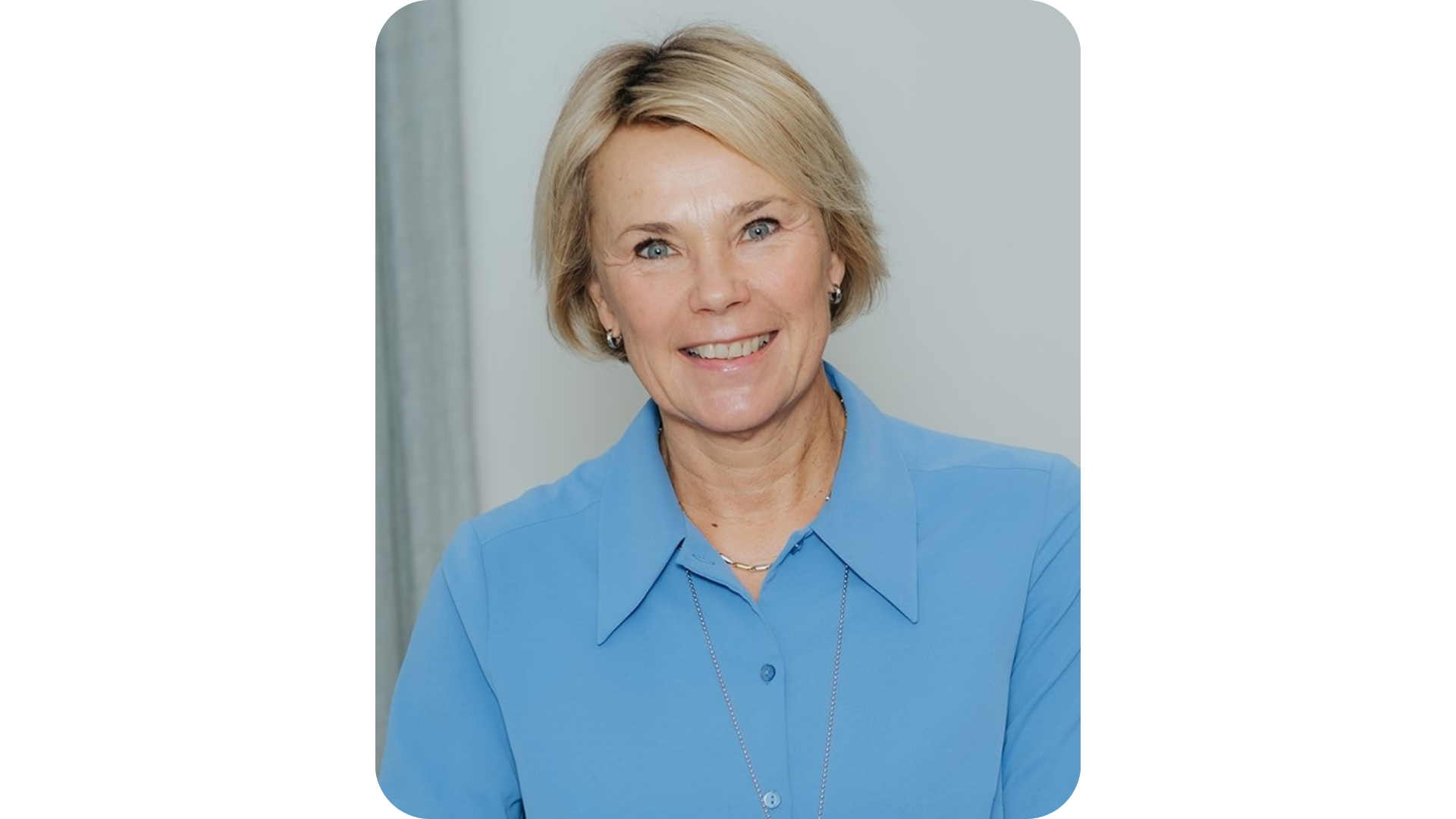 Martina Brandt i blå skjorta ler mot kameran. 