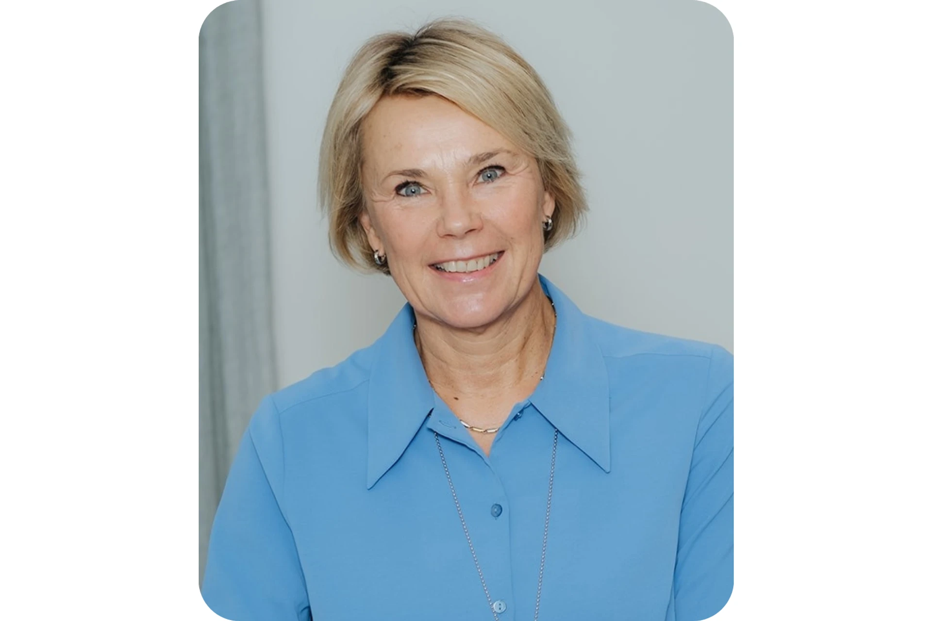 Martina Brandt i blå skjorta ler mot kameran.