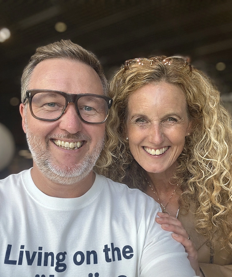 Jens Wedin och Linda Öhling står leende med en tröja Living on the målsnöre