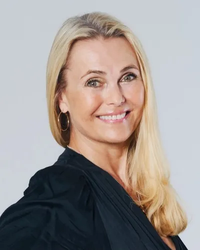 Katarina Mannheimer, föreläsare i svart blus mot grå bakgrund leendes mot kameran