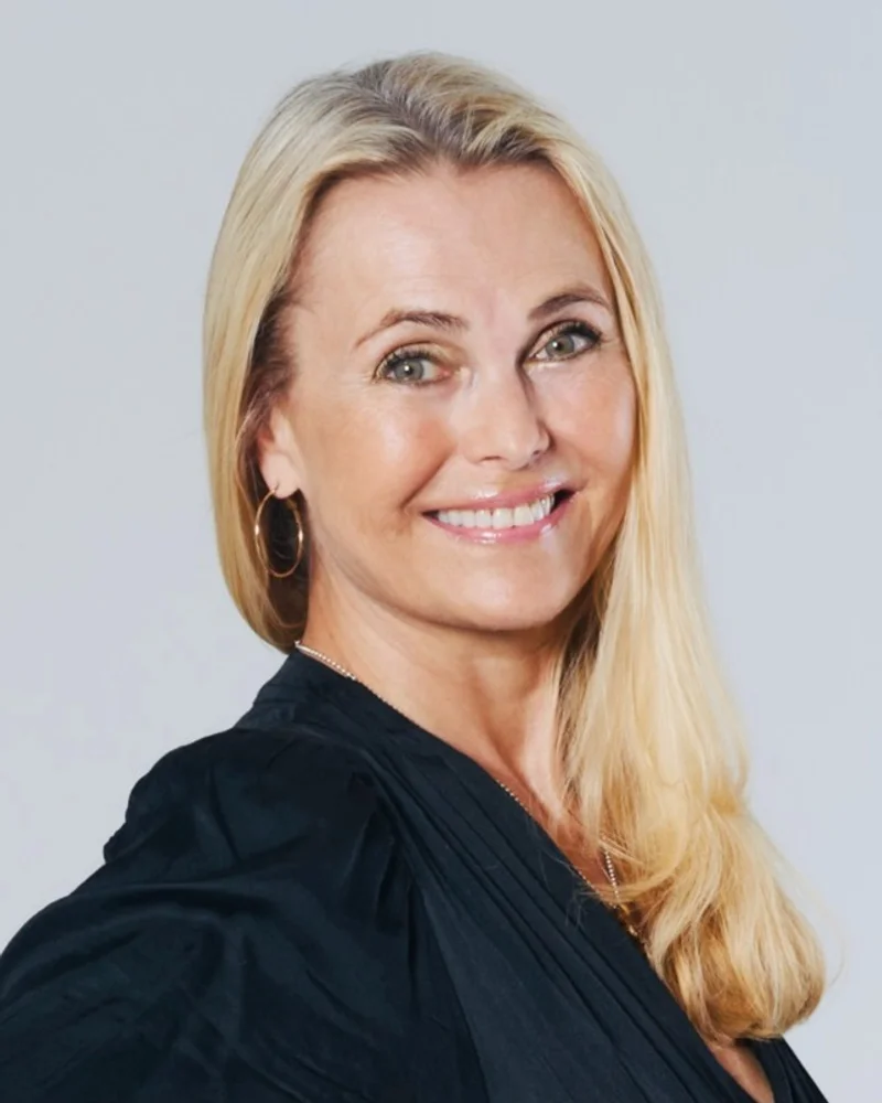 Katarina Mannheimer, föreläsare i svart blus mot grå bakgrund leendes mot kameran