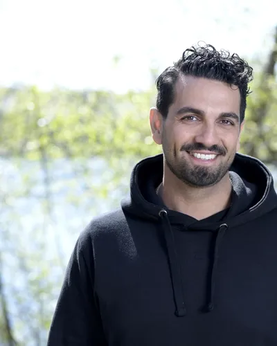 Bilden visar författaren och fd polisen Nadim Ghazale, leende med en sjö och träd i bakgrunden.