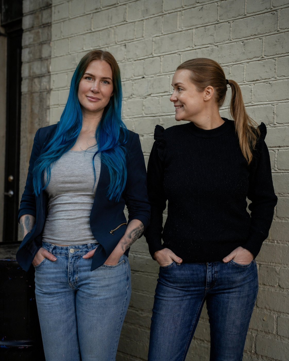 Författarna och föreläsarna Mariah Eriksson och Jenny Hamrén står bredvid varandra framför en tegelvägg.