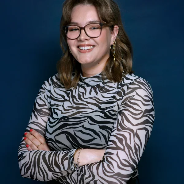 Emilia Markhill har en spräcklig topp på sig och glasögon. Hon ler in i kameran.