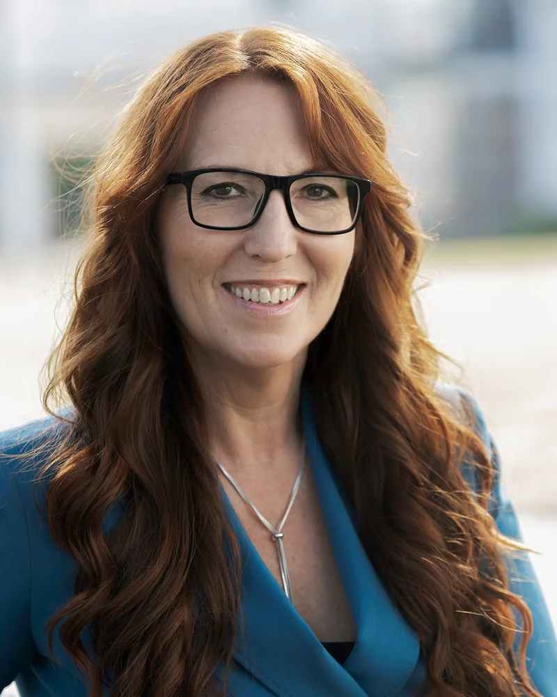 Konsulten och författaren Helen Rigamonti ler in i kameran, hennes röda hår faller ner över den blå kavajen.