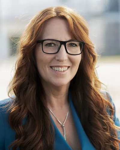 BYWRTRS medlem Helén Rigamonti som utbildar i CX och kundledarskap sitter i blå kavaj och glasögon.