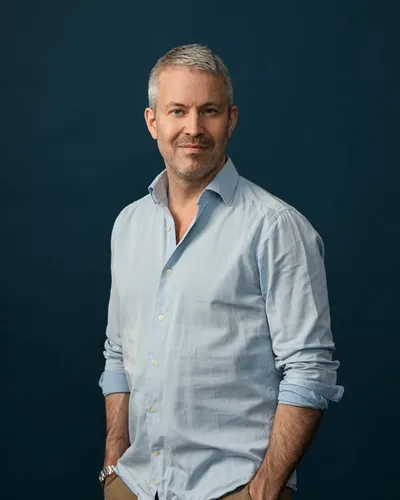 Bilden visar psykologen Björn Hedensjö leende, klädd i blå skjorta.