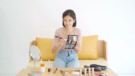 Asian woman holding eye makeup palette