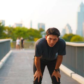 Asian man panting on a bridge.