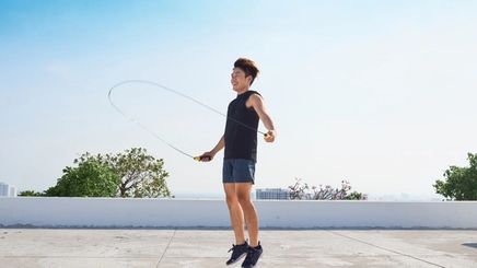 Asian man in black jumping rope outdoors