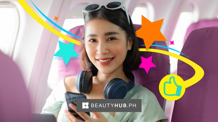 Asian woman with headphones around her neck sitting in a plane.